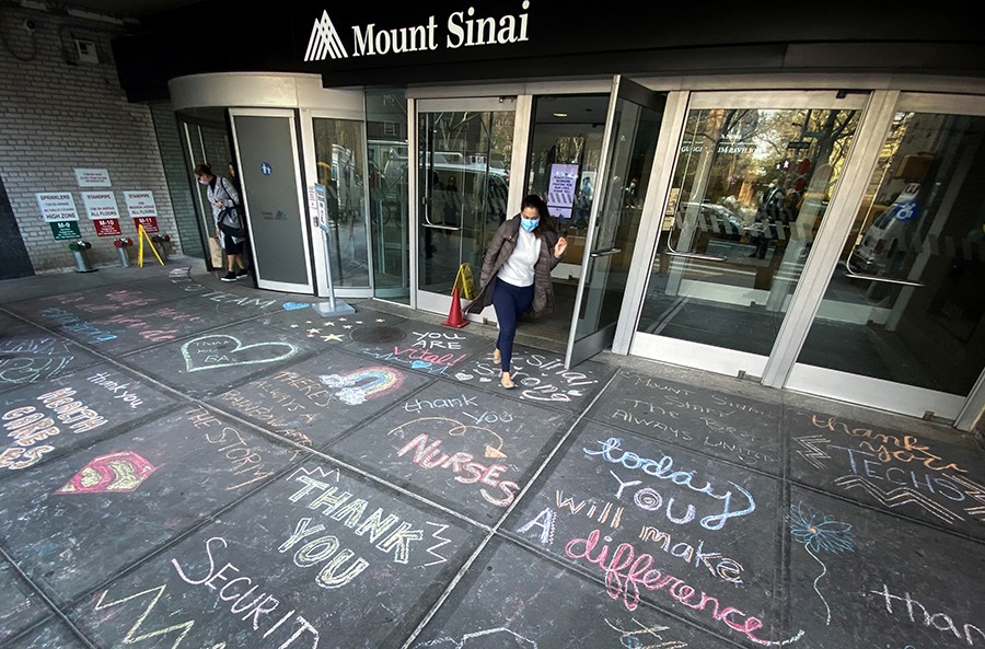 A woman exits Mount Sinai Hospital in Manhattan past messages of thanks written on the sidewalk during the outbreak of the coronavirus disease (COVID19) in New York City, New York, U.S.