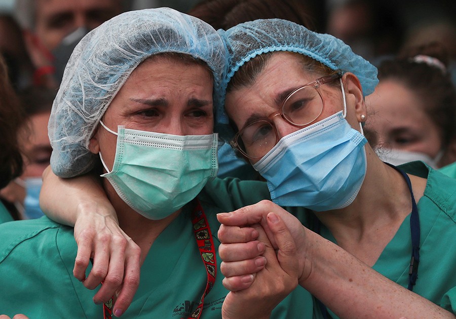 Health workers wearing protective face masks react during a tribute for their co-worker Esteban, a male nurse that died of the coronavirus disease, amid the coronavirus disease (COVID-19) outbreak, outside the Severo Ochoa Hospital in Leganes, Spain